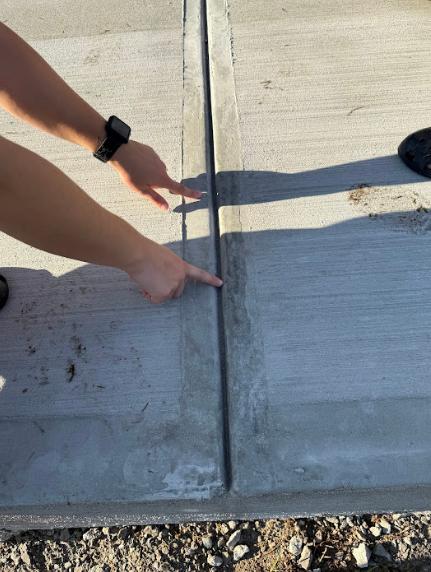 A concrete contractor pointing at a concrete driveway.