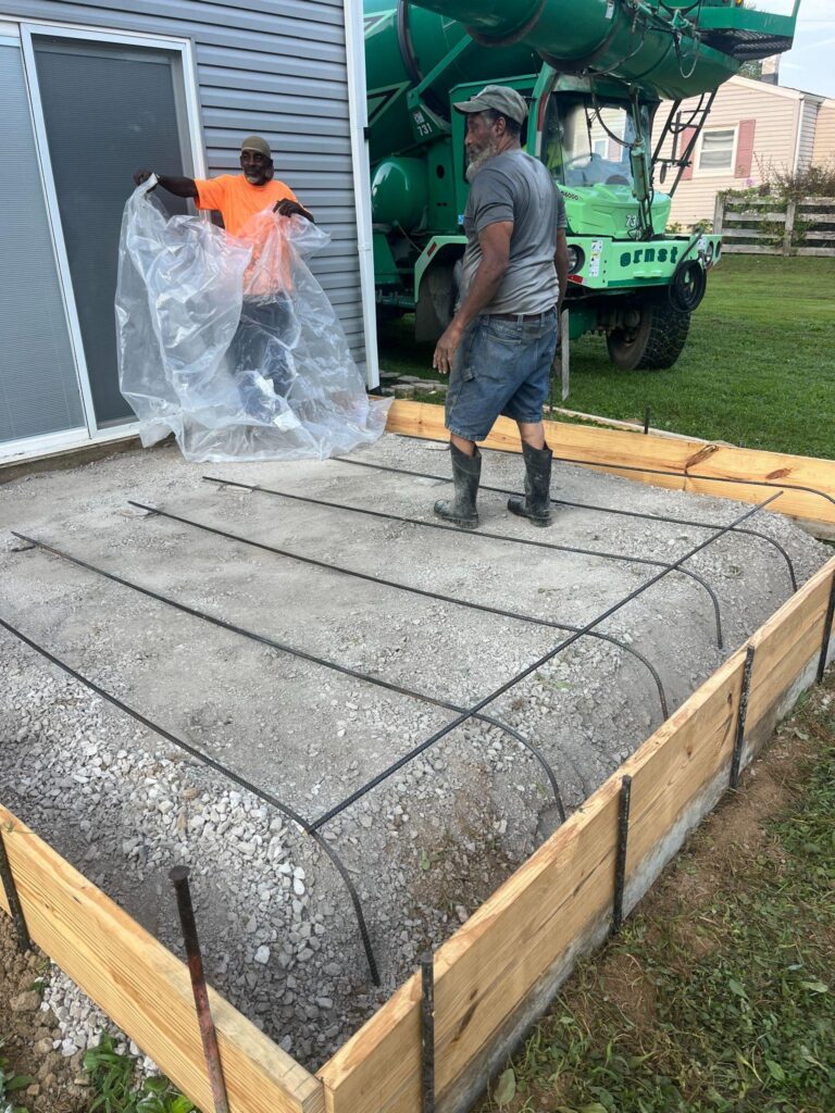 Concrete patio installation in progress behind a local single-family home