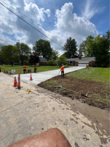 Concrete workers completing a driveway project with a home and garage in the background